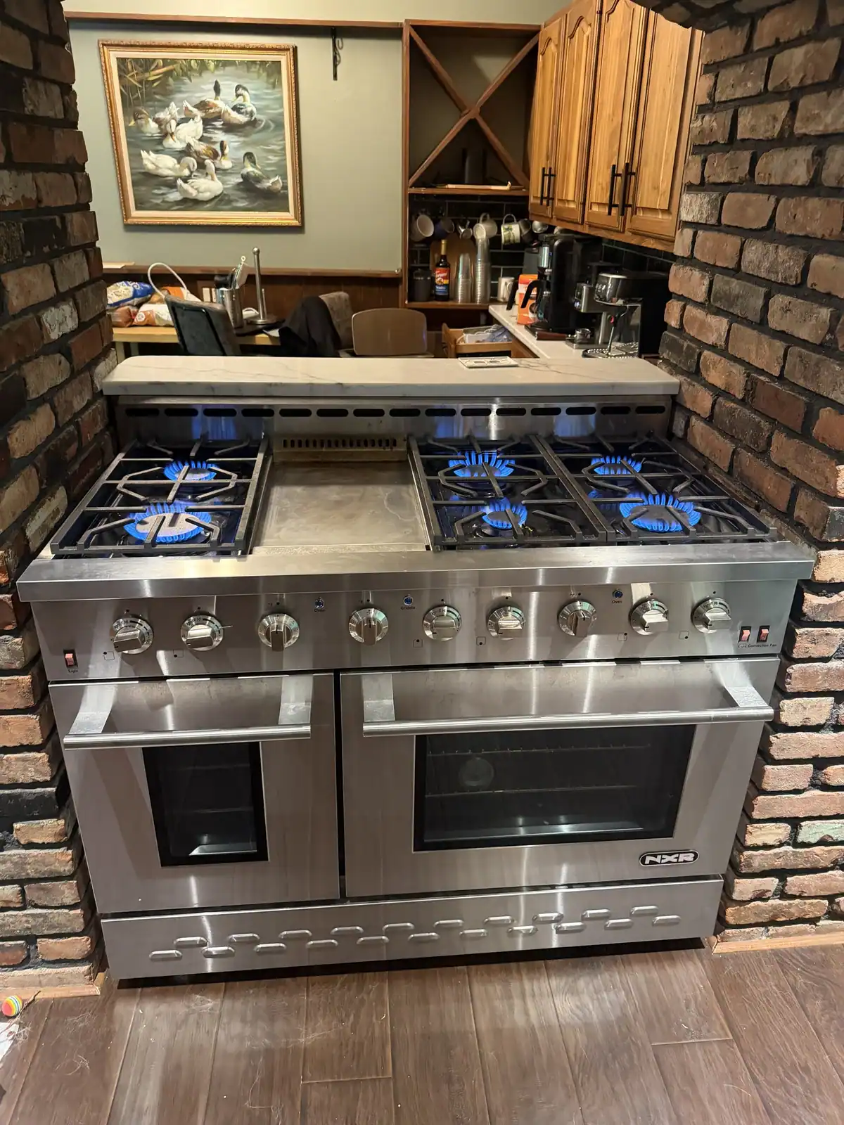 Stainless gas range with six burners and a griddle in a home kitchen
