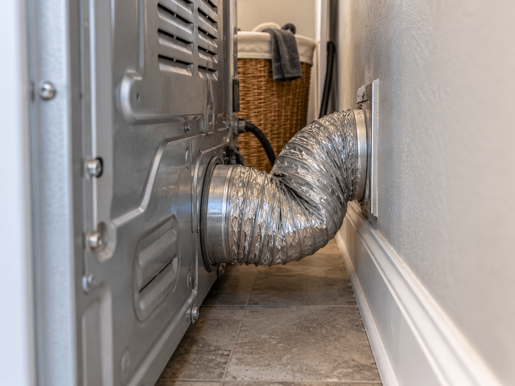 Crushed dryer exhaust duct behind a clothes dryer positioned too close to the wall