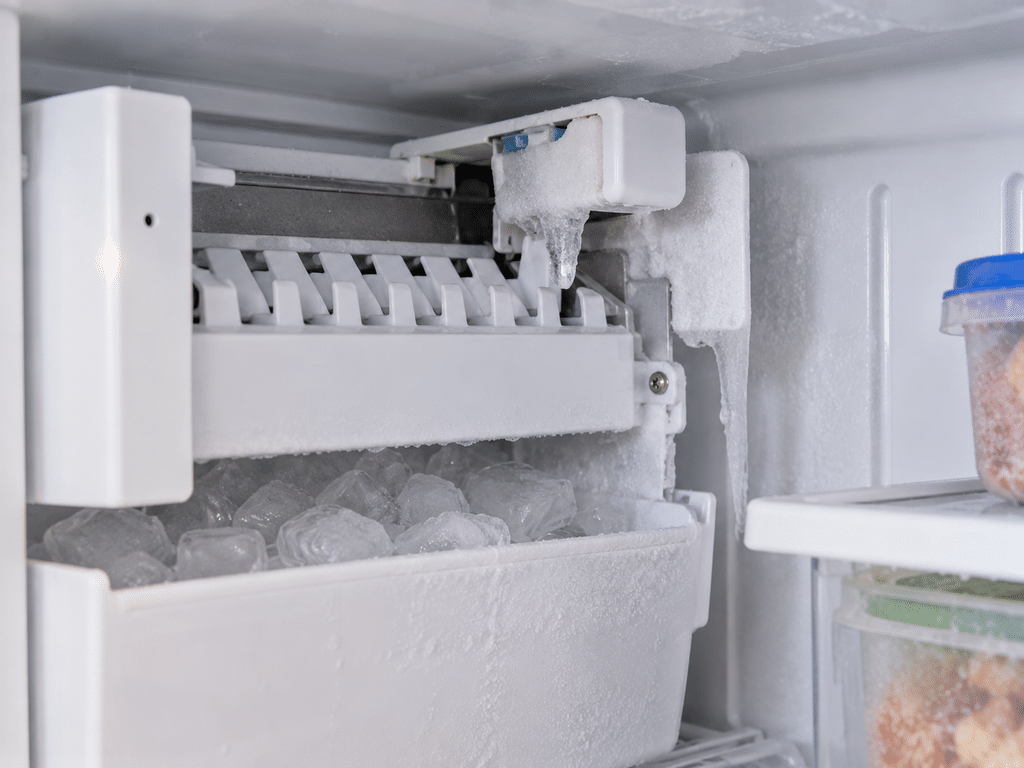 Small ice buildup and frozen droplets near a refrigerator ice maker